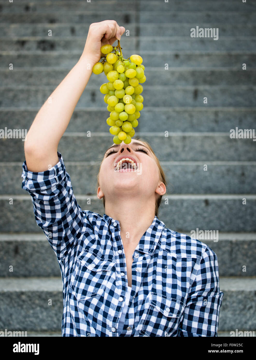 Junge Frau essen Trauben im Freien sitzen auf Treppen Stockfoto