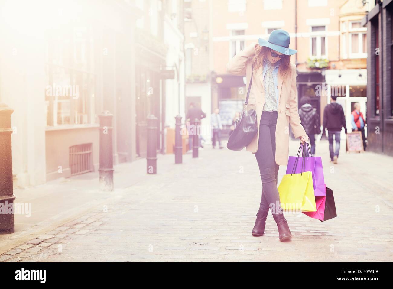 Porträt der stilvolle junge Frau mit Einkaufstüten, London, UK Stockfoto