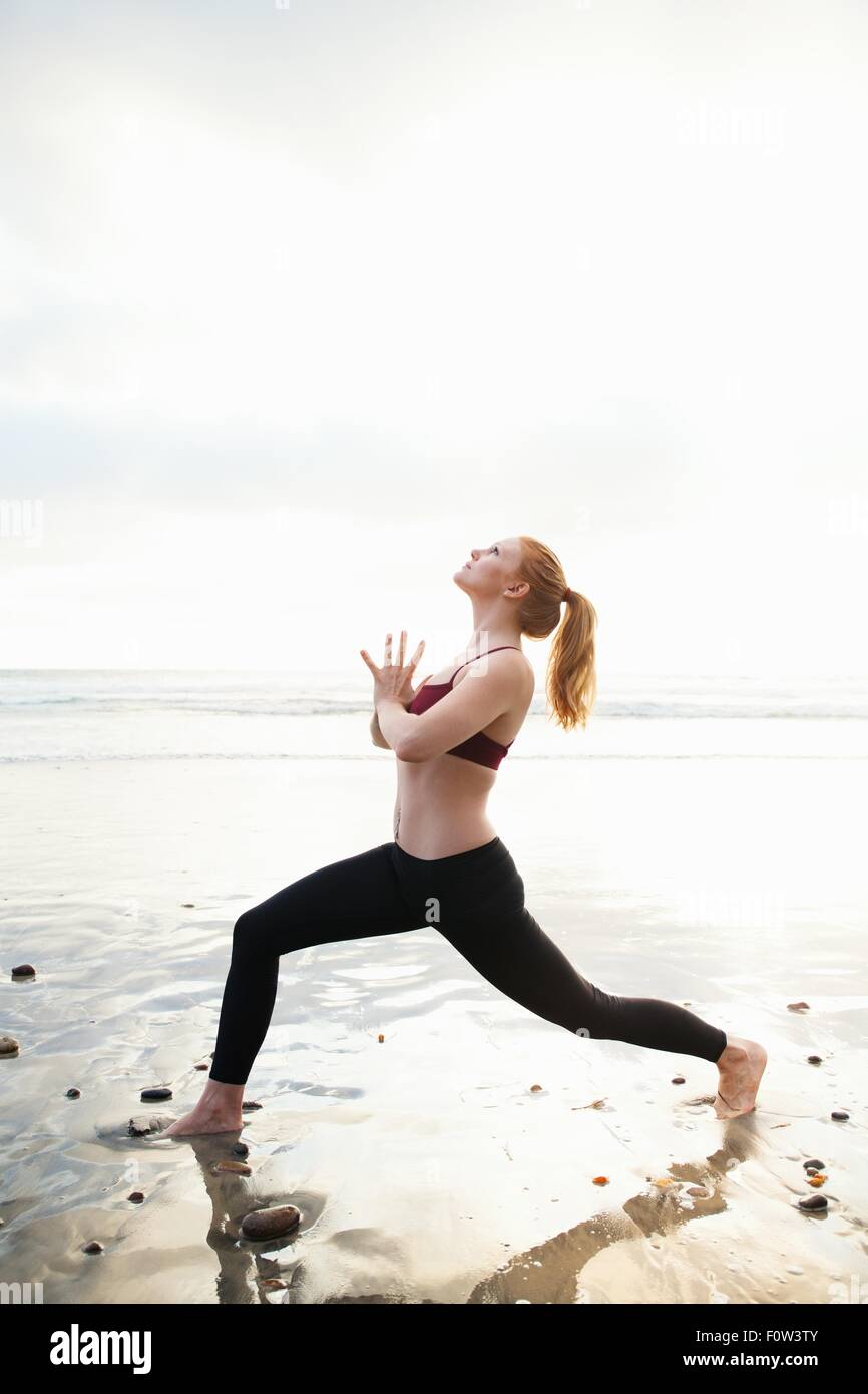 Mitte Erwachsene Frau üben Krieger-Pose am Strand Stockfoto