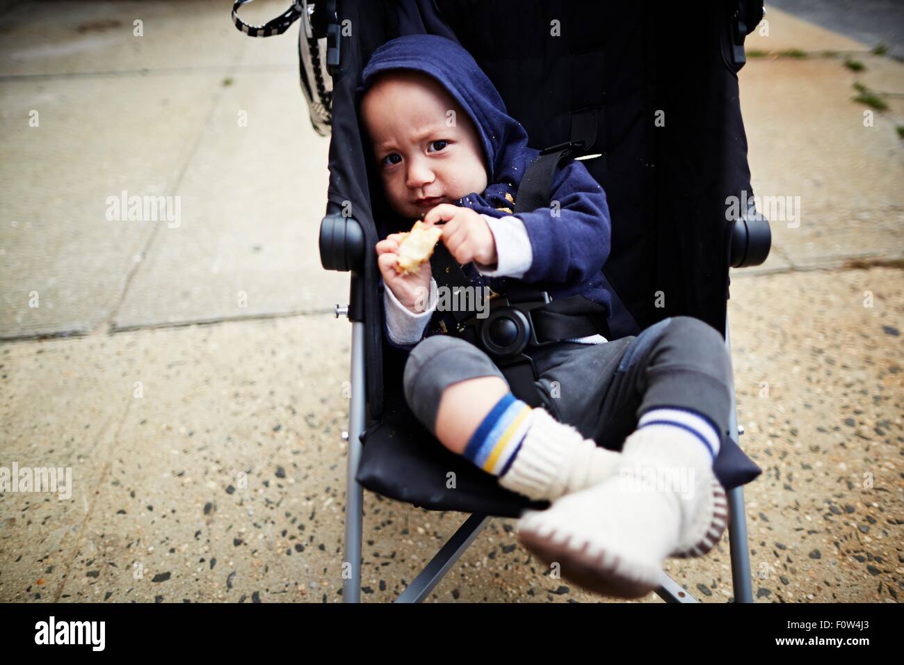 Baby Boy holding Cookie in Kutsche Stockfoto