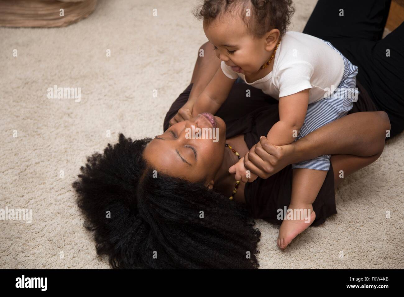 Mitte Erwachsene Frau spielt mit Kleinkind Tochter auf Teppich Stockfoto