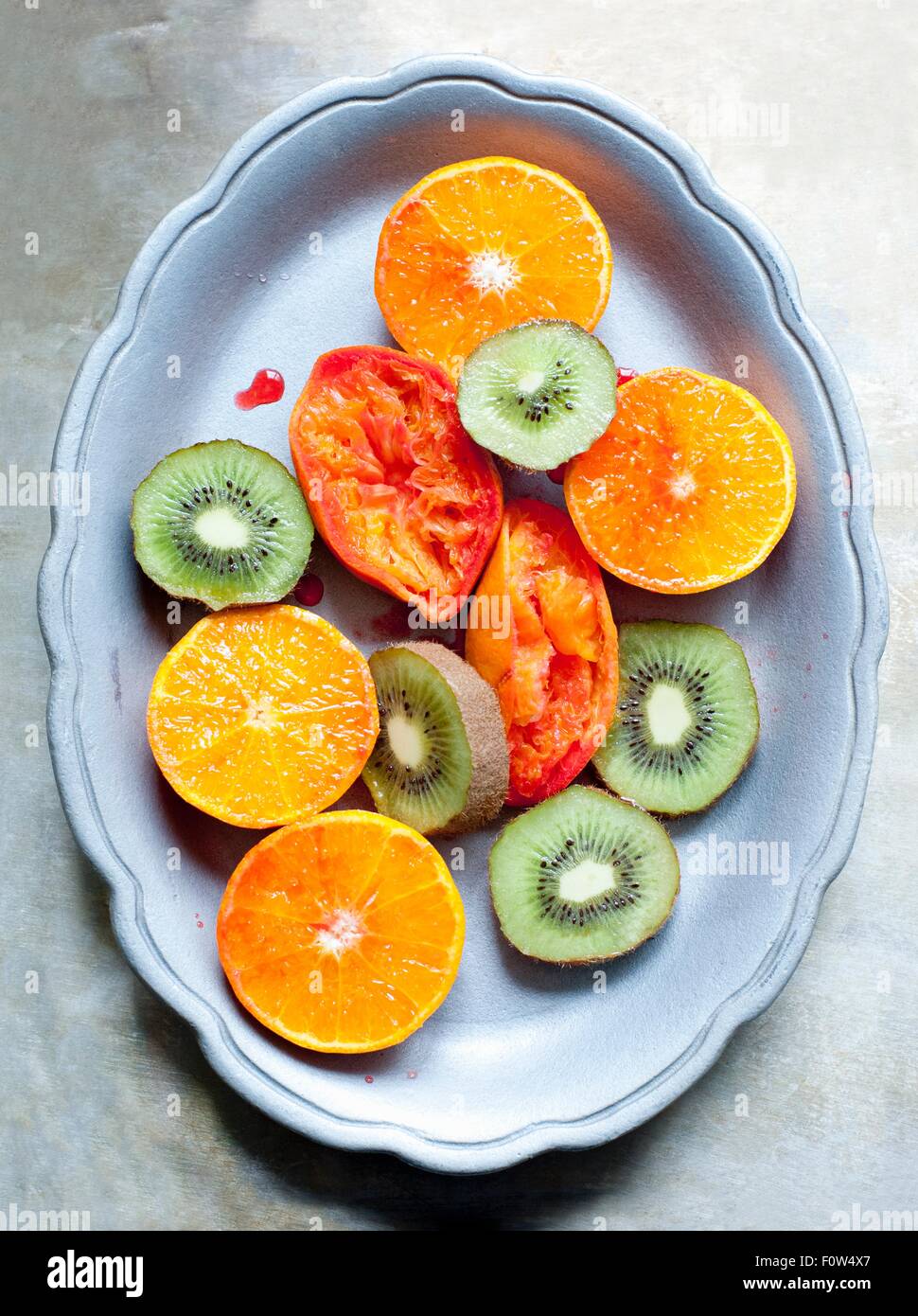 Schüssel mit in Scheiben geschnittenen Kiwi und orange Frucht und gepresste Blutorange Stockfoto