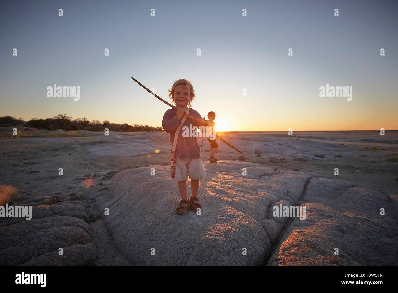 Porträt des jungen stehen auf Felsen, hält Speer, Sonnenuntergang, Gweta, Makgadikgadi, Botswana Stockfoto