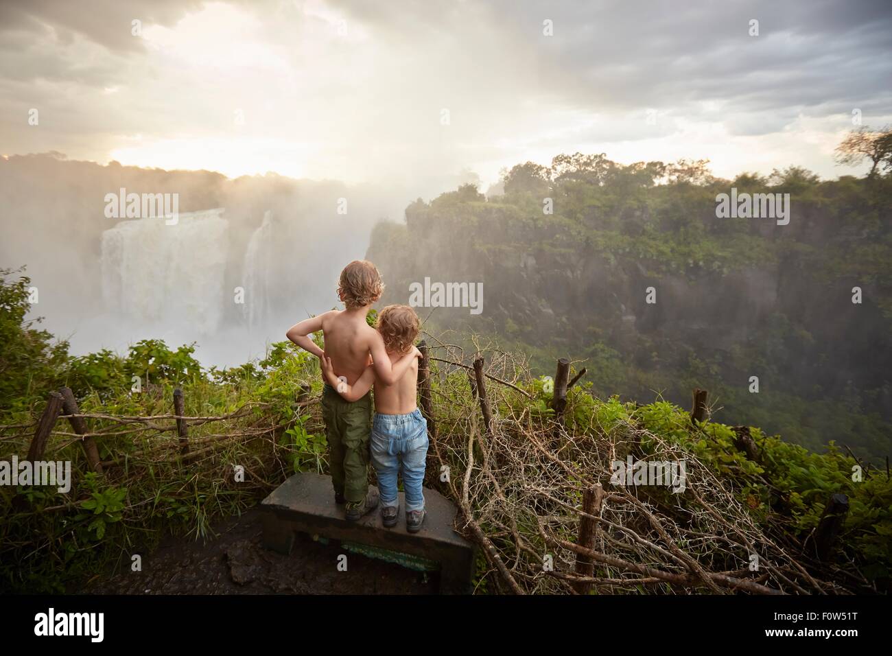 Zwei junge Burschen stehen auf Felsvorsprung bewundern die Aussicht, Rückansicht, Viktoriafälle, Livingstone, Simbabwe Stockfoto