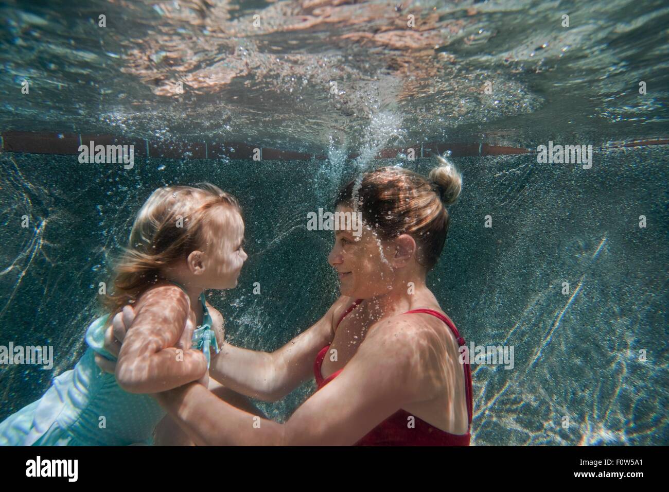 Unterwasser Aufnahme von Mutter-Holding-Tochter und ihr schwimmen lernen zu helfen Stockfoto