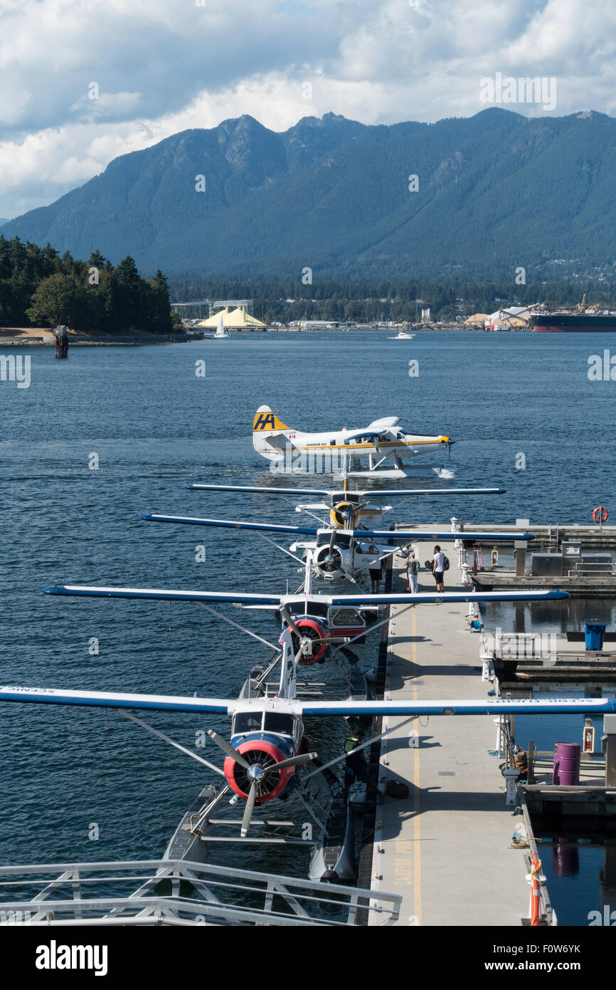Kleinen Wasserflugzeuge auf einem Steg im Hafen von Vancouver, mit einem Flugzeug Kreuzung hinter angedockt Stockfoto
