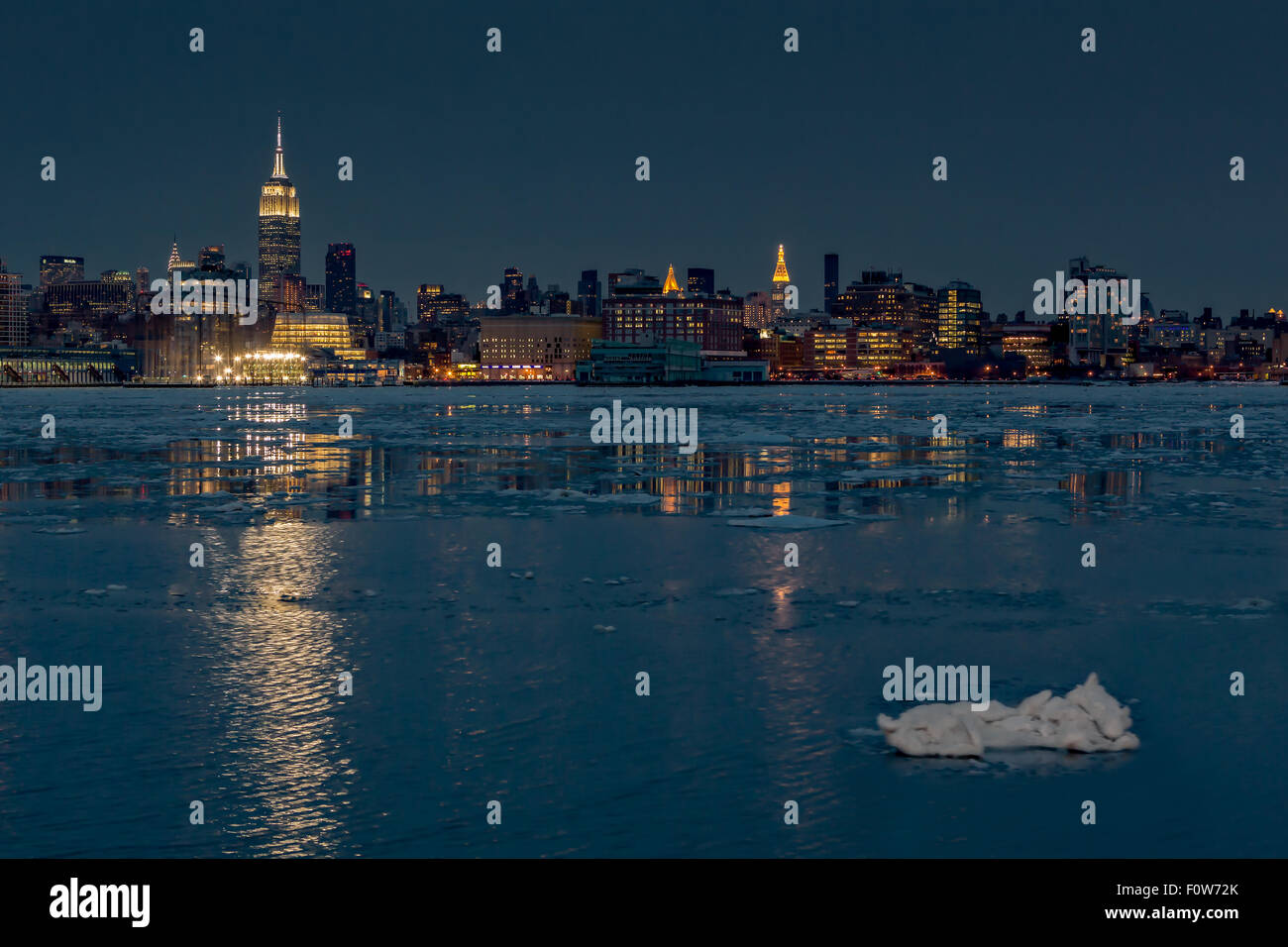 Gefrorene Midtown Manhattan NYC-Midtown Manhattan, New York City Skyline mit dem Empire State Building zusammen mit anderen Wolkenkratzer und seitlichem Blick auf das Chrysler Building ist abends beleuchtet. Die Hudson River ist ziemlich viel auf eine klare, aber sehr kühlen Winterabend eingefroren. Der Skyline leuchtet Gebäude Leuchten an der offenen kalten Gewässern während der Blauen Stunde nach Sonnenuntergang wider. Stockfoto