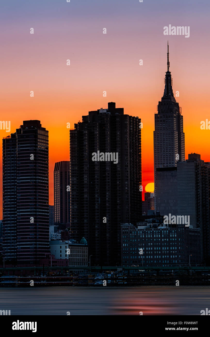 Die untergehende Sonne hinter dem Empire State Building aus Long Island City. Stockfoto