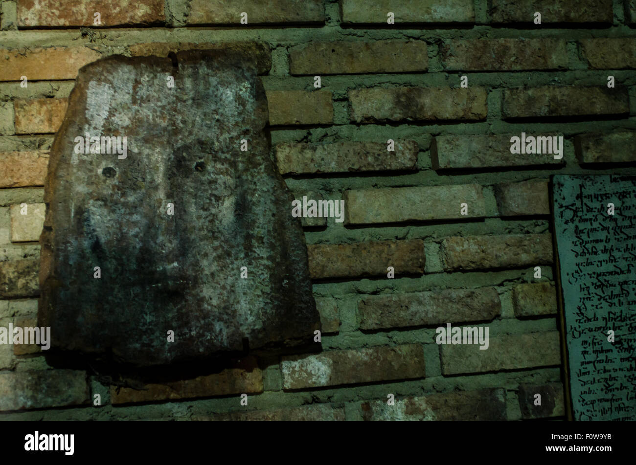 Faszinierende Steinmasken, die auf einer Backsteinmauer in einer historischen Stätte mit antiken Inschriften ausgestellt sind Stockfoto