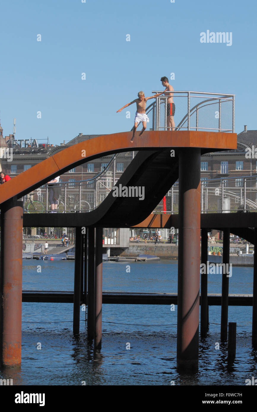 Boy Jumping from Kalvebod Bølge, Kalvebod Wellen im inneren Hafen von Kopenhagen bei Kalvebod Brygge. Urbaner Raum, sozialer Hub, Veranstaltungsort für Wassersport Stockfoto