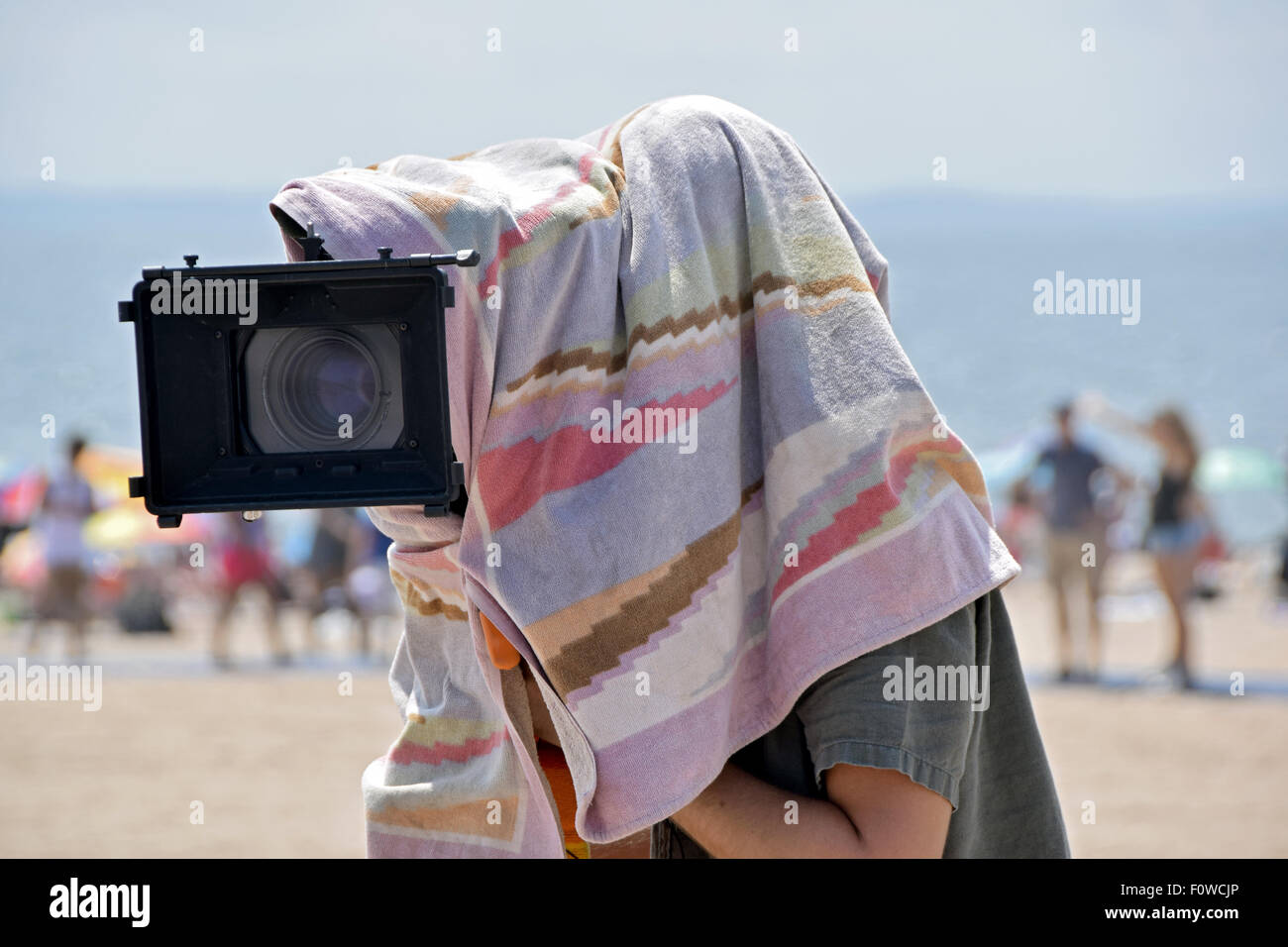 Ein Kameramann Fotografieren an einem sehr heißen Tag am Strand von Coney Island, Brooklyn, New York Stockfoto