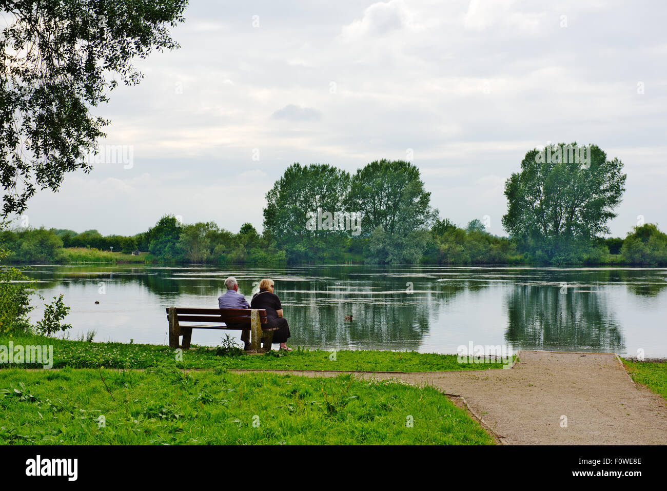 Älteres Paar auf Bank mit Blick auf See, St. Chad es Wasser aus Wilne Rd, Derby Stockfoto