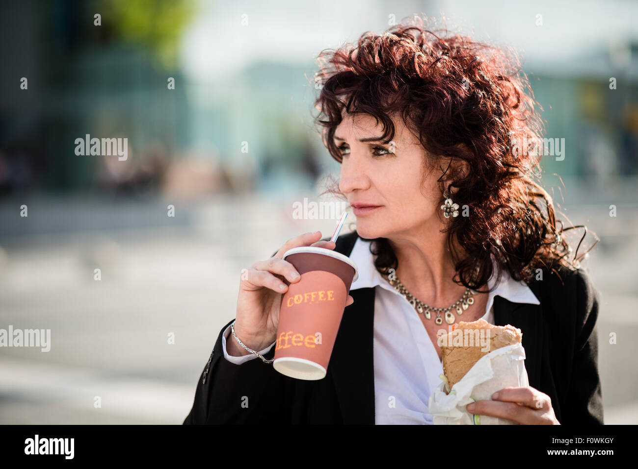 Senior Business-Frau Fast-Food-Mittagessen - sandwich zum Mitnehmen Kaffee zu trinken und Essen in der Straße Stockfoto