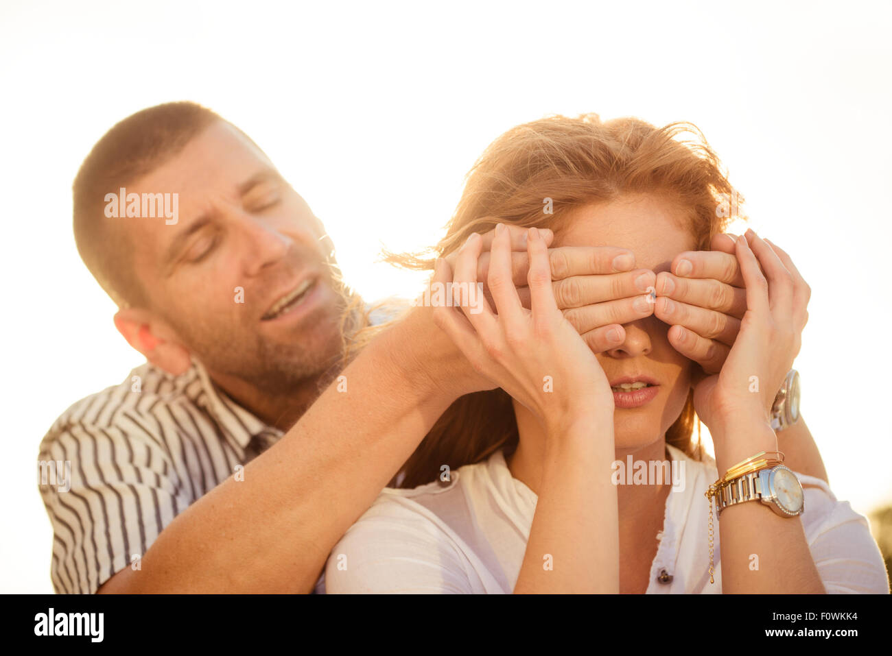Man deckt Augen warten Frau und versteckt sich hinter ihr Stockfoto