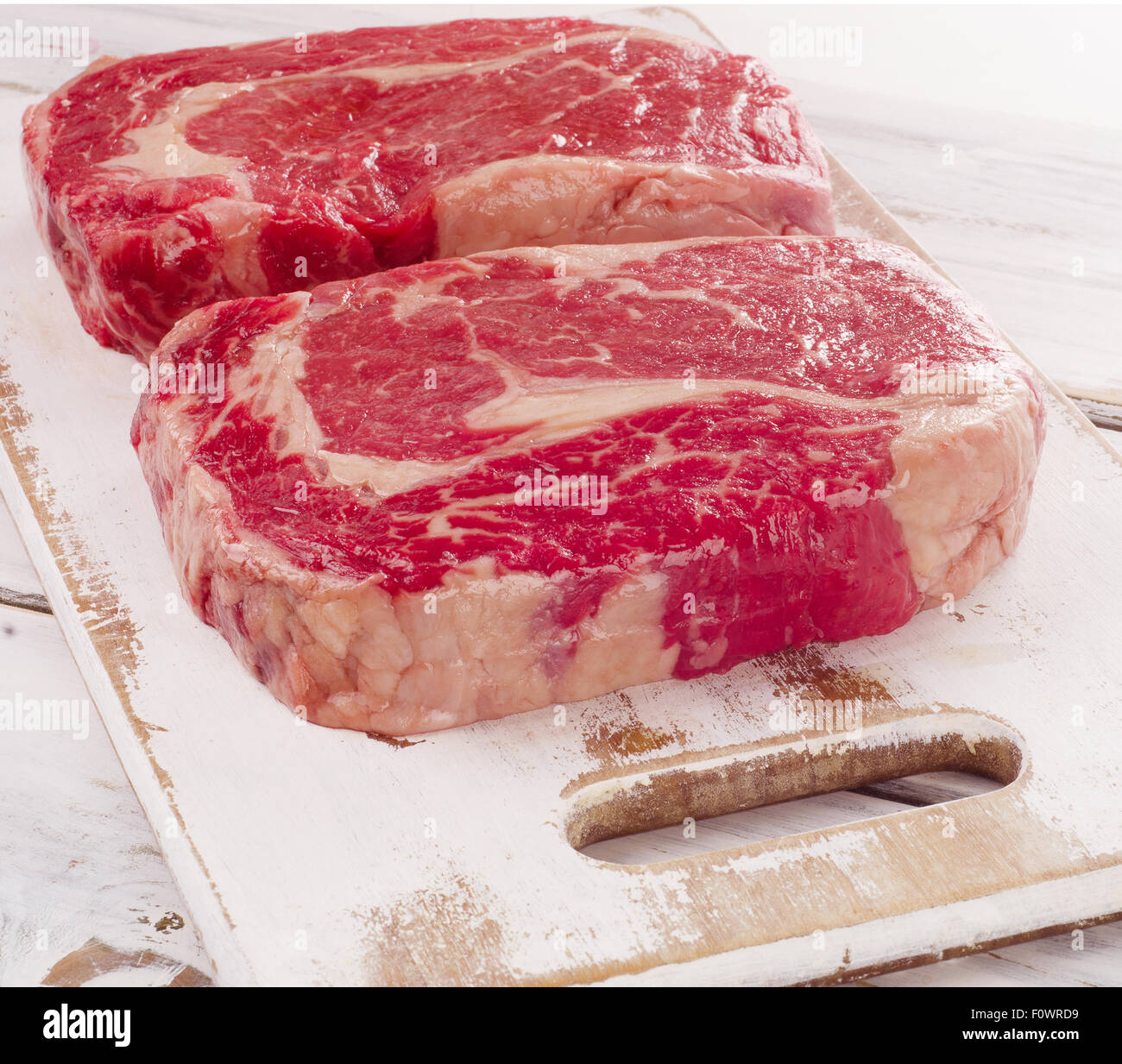 Rohe frische Ribeye-Steak auf einem Holzbrett. Stockfoto