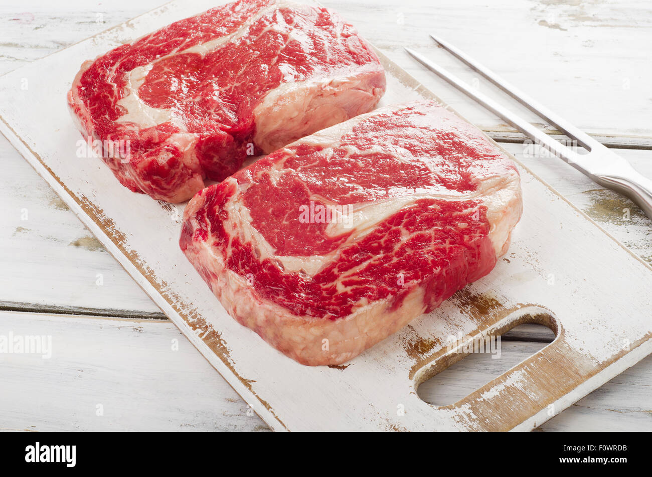 Rohes Frischfleisch Ribeye Steak auf einem weißen Hintergrund aus Holz. Stockfoto
