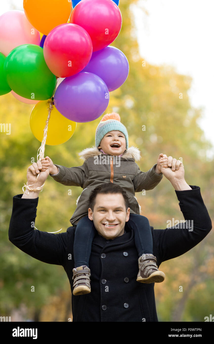 glücklicher Vater werfen kleine Kind mit Luftballons, Ausflug im Herbst park Stockfoto