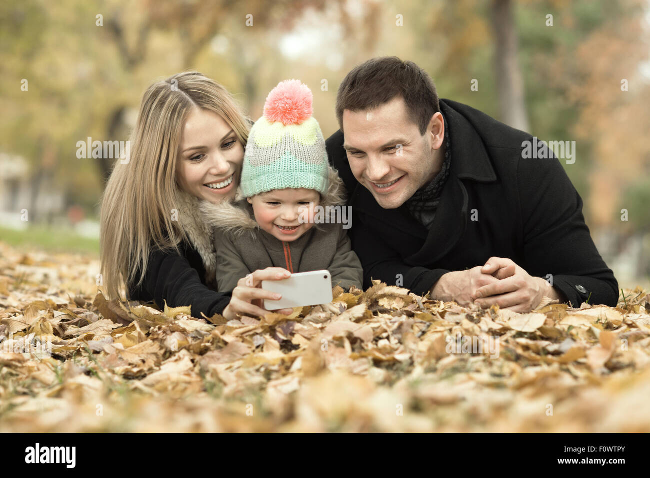 glückliche Familie mit Kleinkind nehmen Selfie am Telefon, im Herbst Park Ausflug Stockfoto