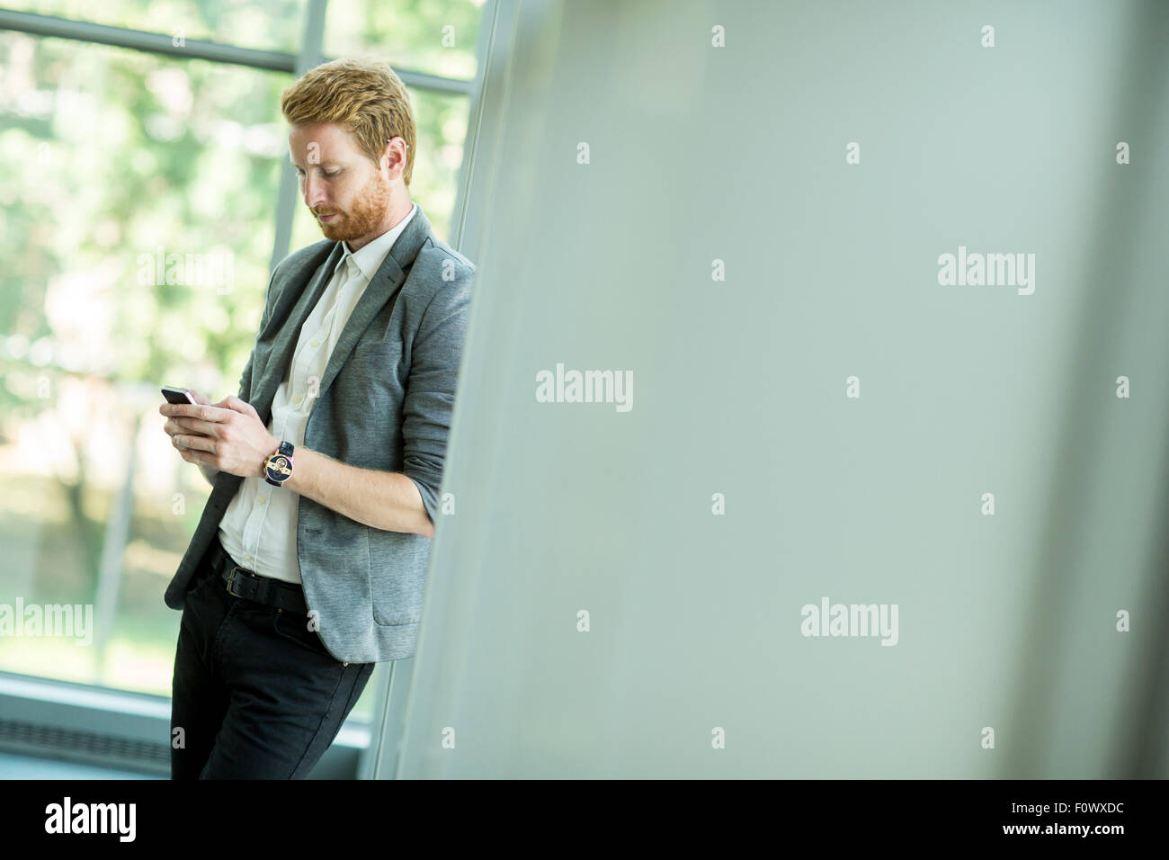 Junger Mann mit Handy im Büro Stockfoto