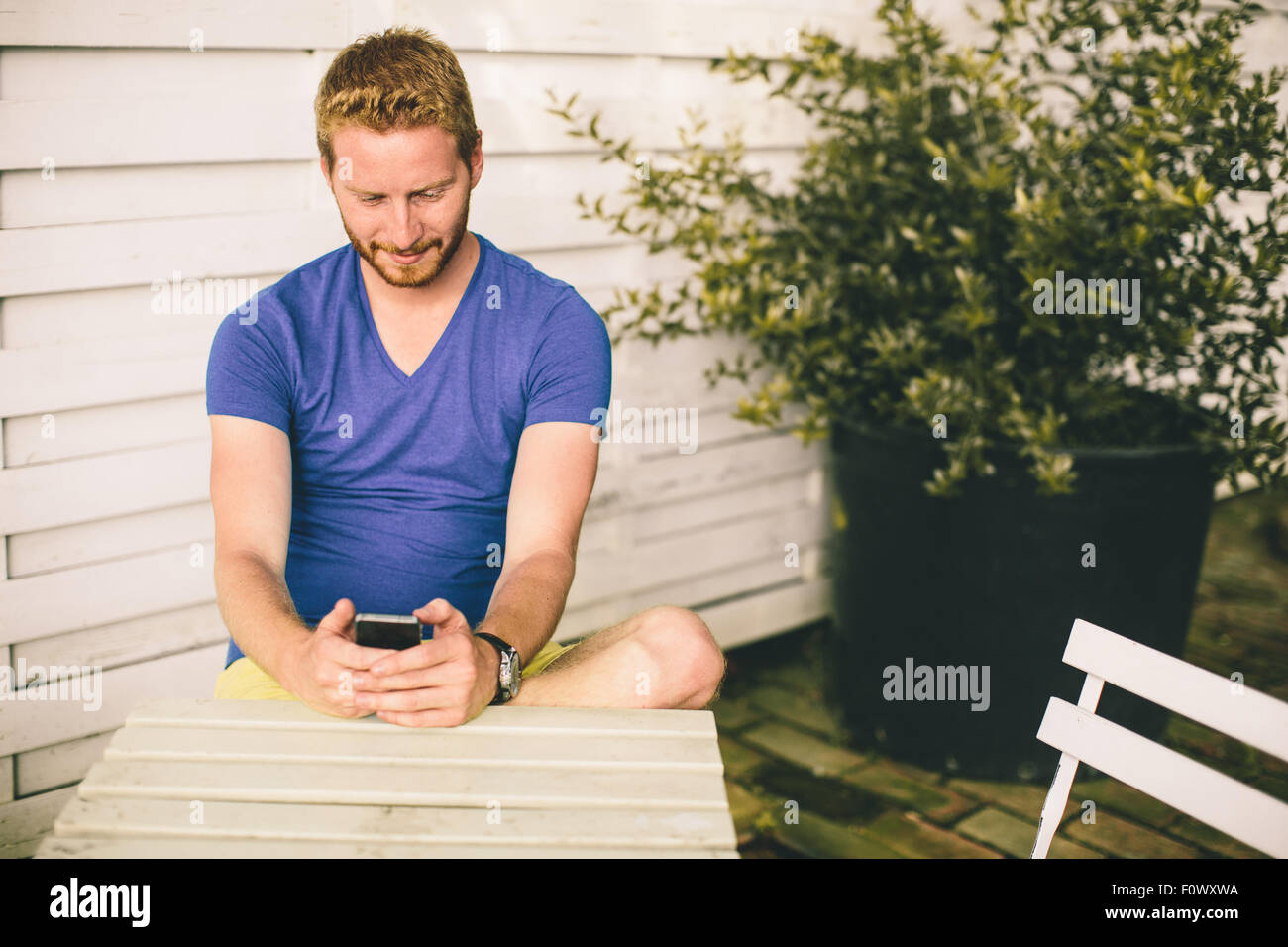 Junger Mann sitzt im Café mit Handy Stockfoto