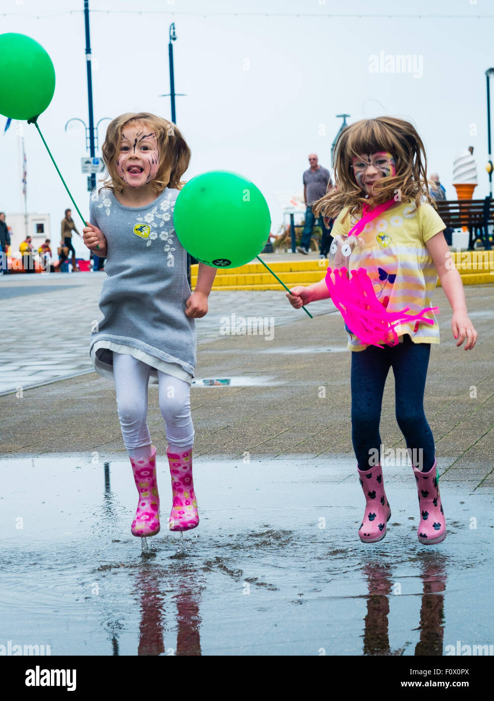 Aberystwyth, Wales, UK. 22. August 2015. Zwei junge Mädchen viel Spaß beim plantschen in einer Pfütze von Regenwasser auf einer nassen Nachmittag. Während ein Großteil der Südosten von Großbritannien in heißen trockenen Sonne mit dem Effekt "Spanisch Plume" sonnt, ist im Westen viel schlechter Wetter erleben. Eine Kaltfront aus dem Norden bringt schwere Regen und bewölktem Himmel in Aberystwyth am Tag des jährlichen "Meer zum Ufer Food Festival" statt auf das Resort Promenade. Die Wahrscheinlichkeit ist für die ungeklärten Bedingungen herrschen für viel der nächsten Woche zu Photo Credit: Keith Morris/Alamy Live News Stockfoto