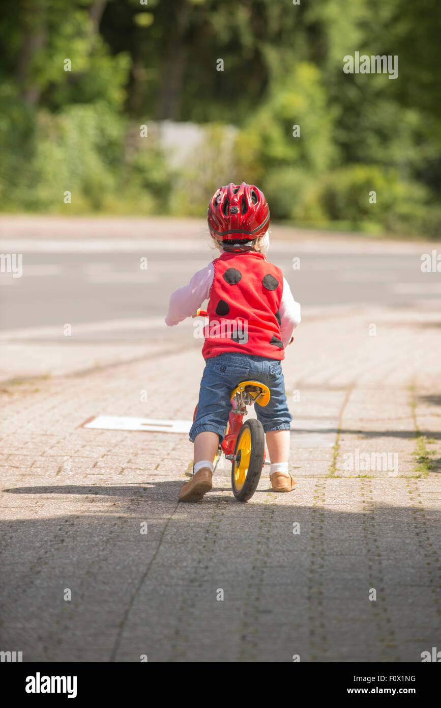 Kleines Mädchen auf dem Fahrrad auf dem Bürgersteig mit Sturzhelm. Stockfoto