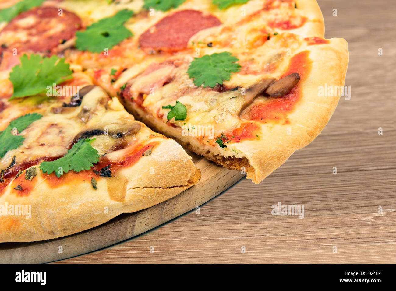 Hausgemachte Pizza an Bord am Holztisch Stockfoto