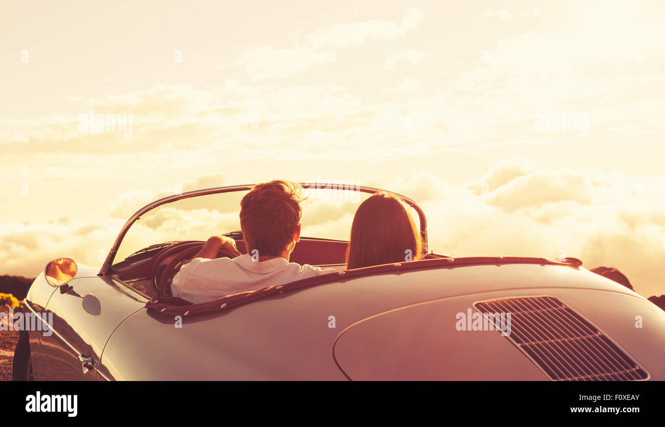 Romantische junge attraktive paar den Sonnenuntergang im klassischen Oldtimer Sportwagen Stockfoto