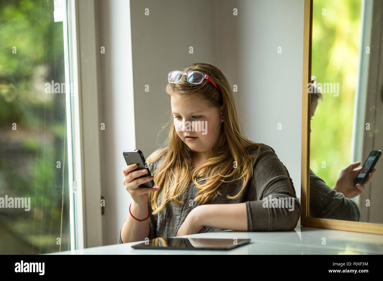 Teenager-Mädchen sitzt an einem Tisch auf einem Smartphone eingeben. Stockfoto