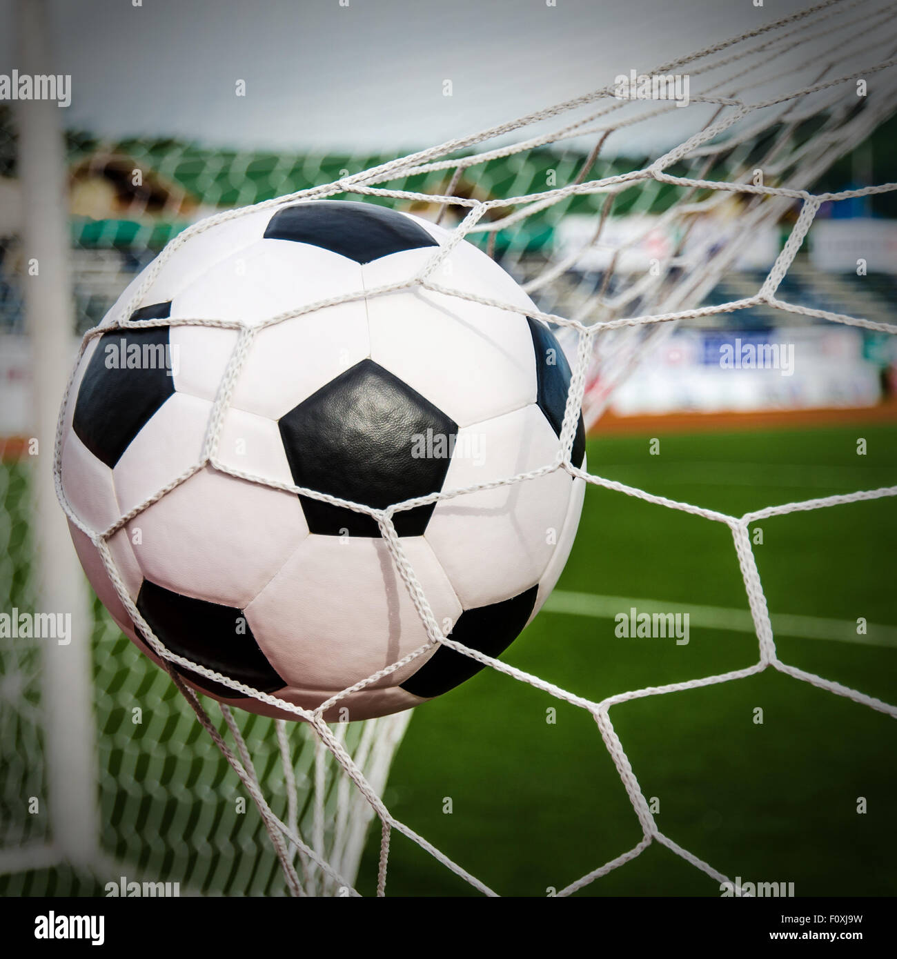 Fußball im Tor-Netz mit grünen Wiese. Für Sport-Konzept. Stockfoto