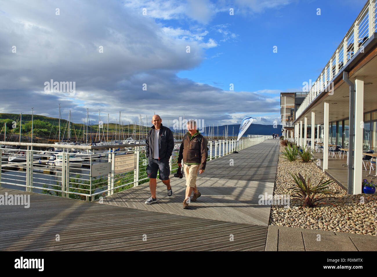 Zwei Männer zu Fuß entlang der Promenade am Portavadie Marina am Loch Fyne in Argyll, Schottland Stockfoto