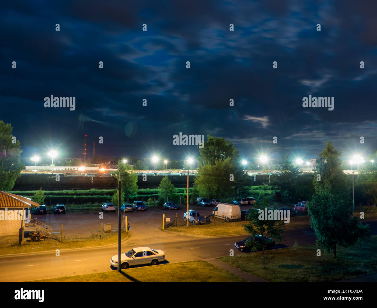 Parkplatz in der Nacht mit Straßenlaternen und erstaunlich dunkle Wolken Stockfoto