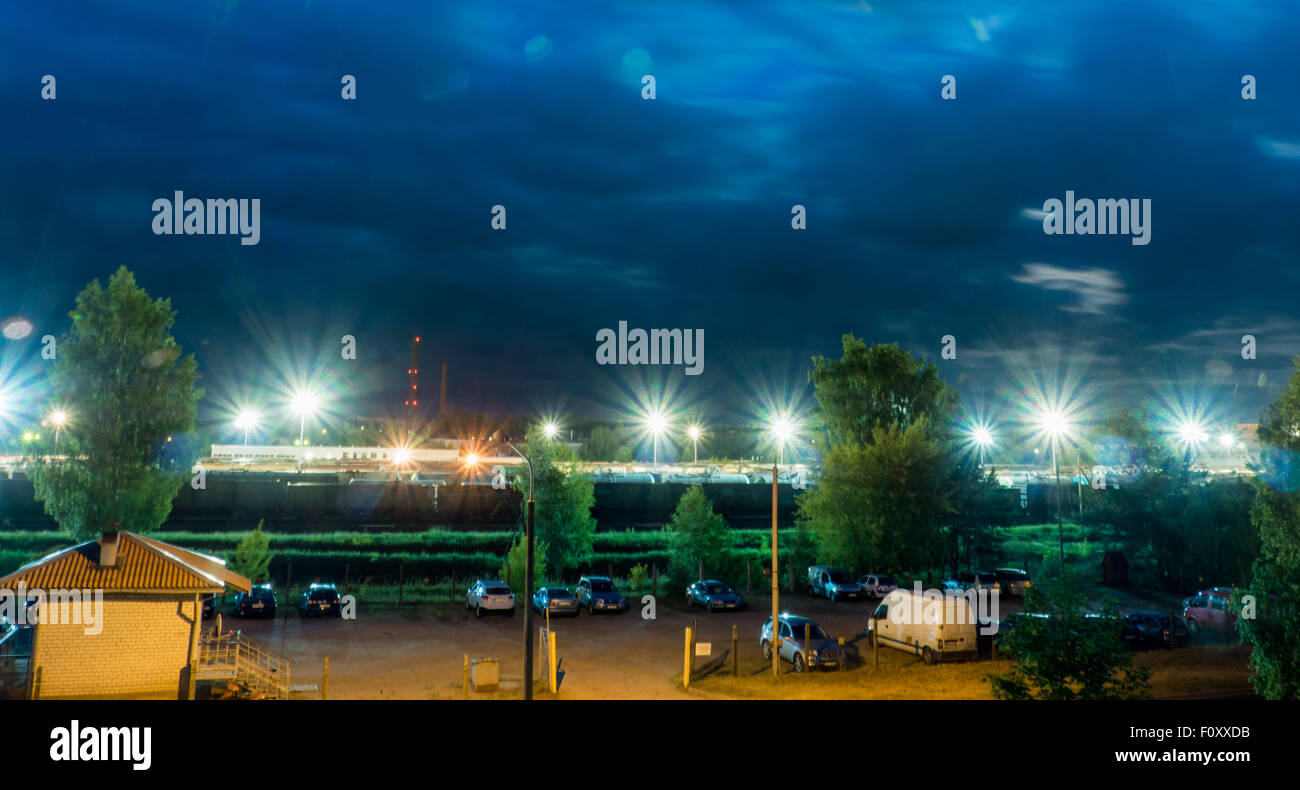Parkplatz in der Nacht mit Straßenlaternen und erstaunlich dunkle Wolken Stockfoto
