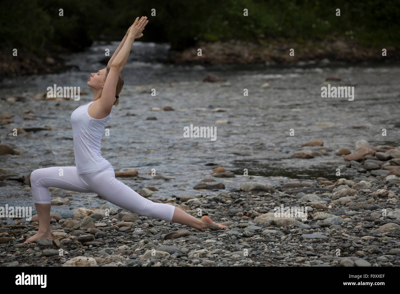 Junge Frau übt Yoga am Stein Ufer Fluss Stockfoto