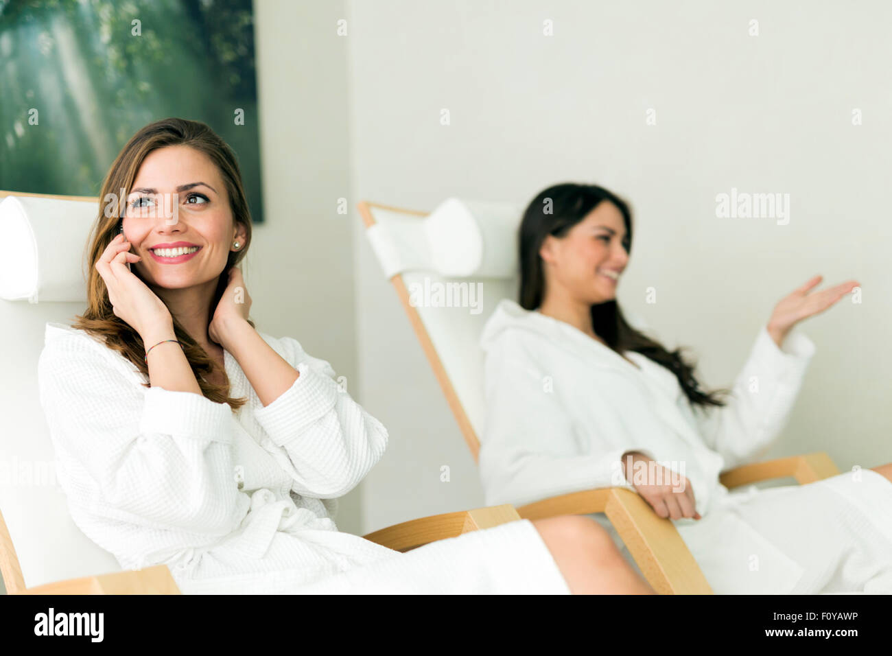Junge und schöne Frauen Entspannung in einem Spa Roben tragen und am Telefon sprechen Stockfoto