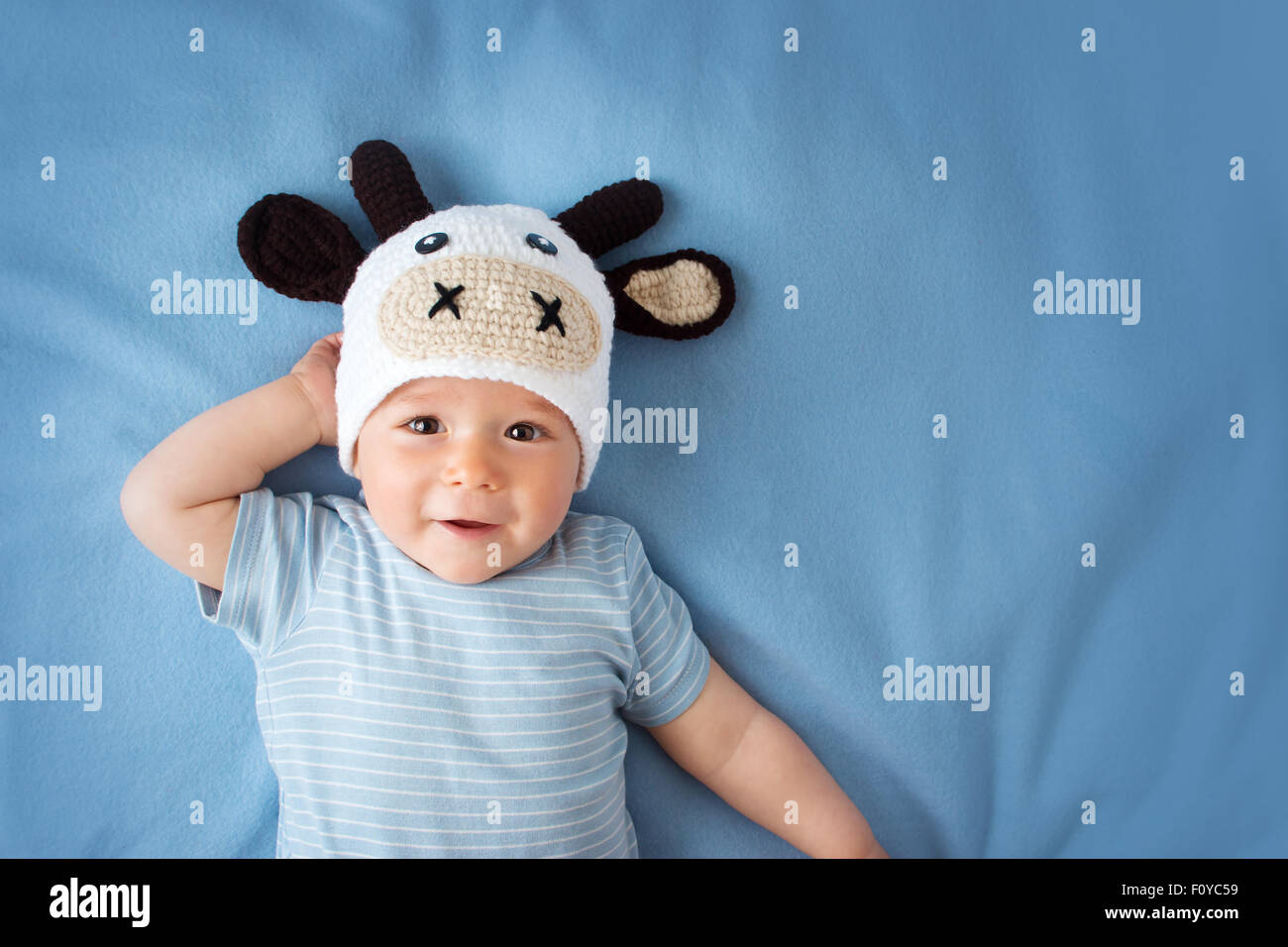 Baby in einem Kuh-Hut auf blaue Decke Stockfoto