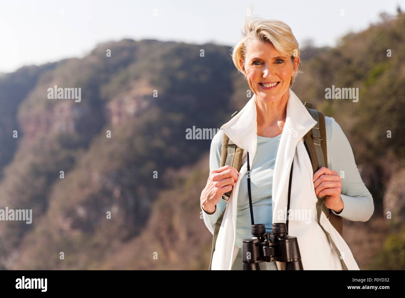 schöne mittlere gealterte Frau oben auf dem Berg mit dem Fernglas Stockfoto