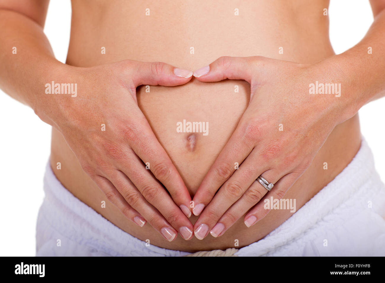Schwangere Frau macht Herzform mit Hände über ihren Bauch Stockfoto