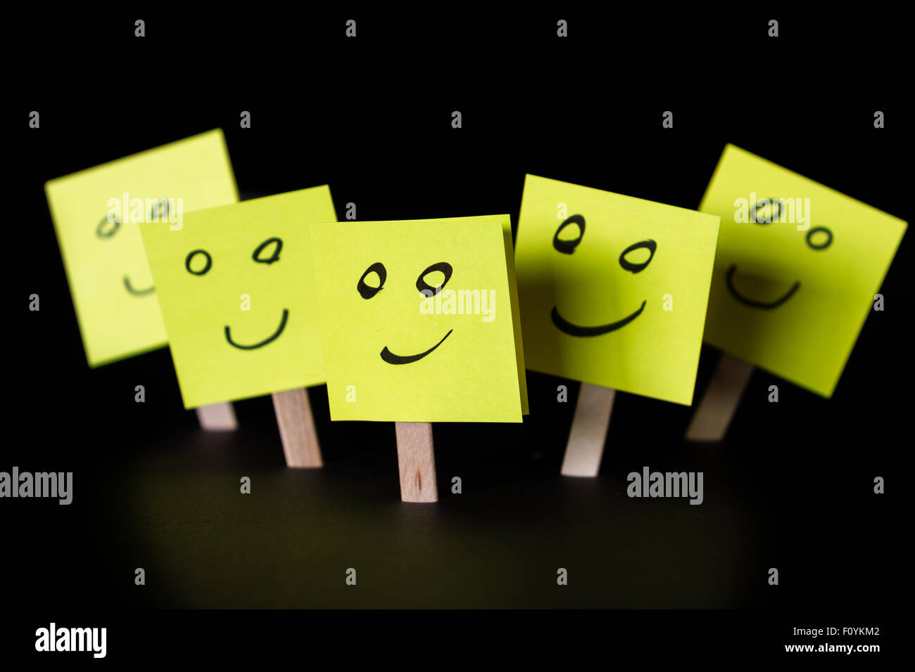 Haftnotizen mit glücklichen Gesichtern isoliert auf einem schwarzen Hintergrund für ein glückliches Team-Konzept Stockfoto