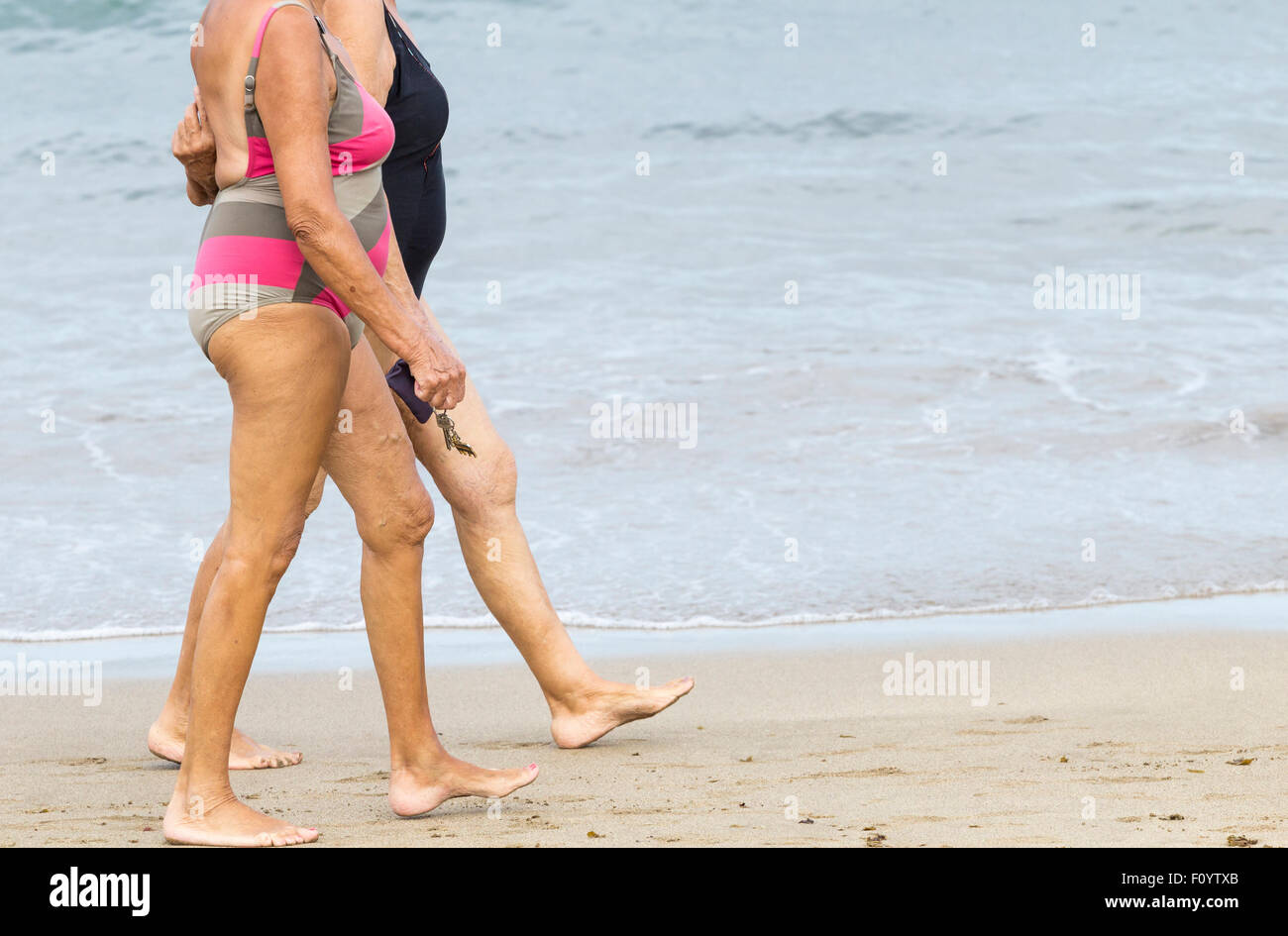 Zwei ältere Frauen, die zu Fuß am Strand Stockfoto