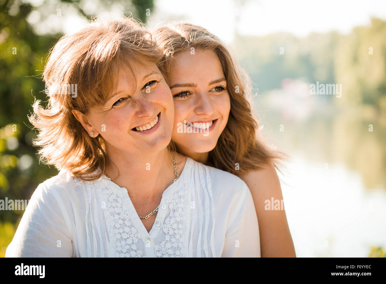 Reife Mutter mit ihrer Tochter im Teenageralter suchen in eine Richtung - Hintergrundbeleuchtung mit Sonne Stockfoto