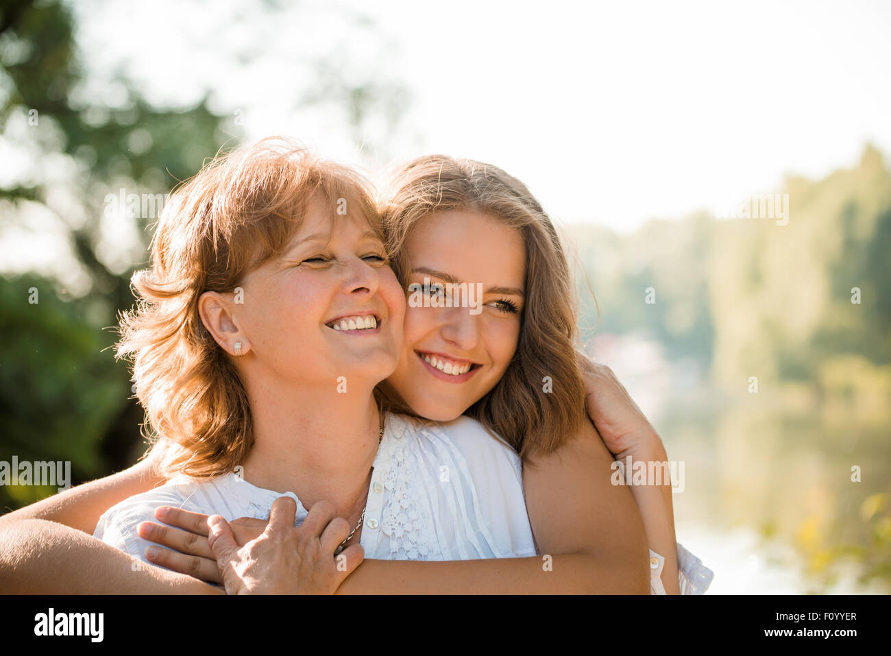 Reife Mutter umarmt mit Teen Tochter in der Natur im Freien an sonnigen Tag Stockfoto