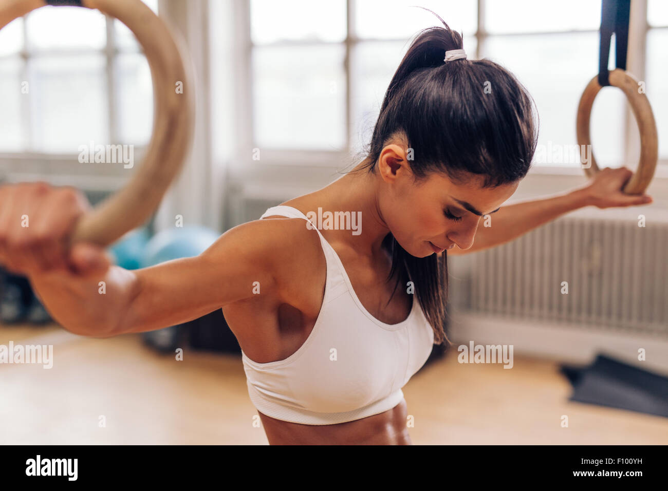 Junge Frau mit Turnerin Ringe in der Turnhalle zu passen. Starke junge Frau im Fitness-Studio trainieren. Stockfoto