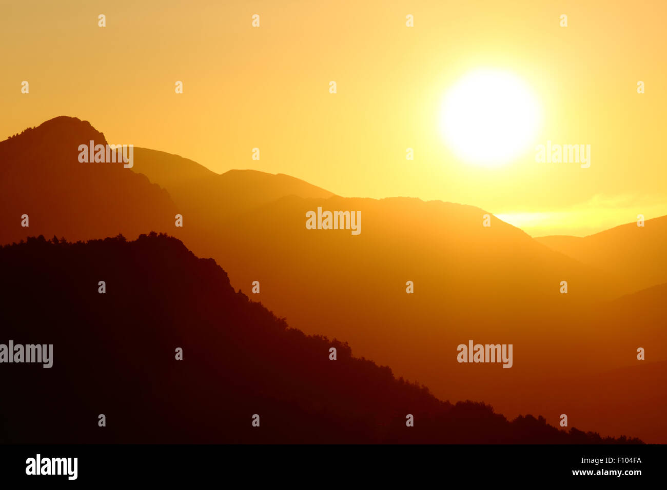 Gegenlicht eines Sonnenuntergangs auf eine Berglandschaft mit einem großen Sonne am Himmel Stockfoto