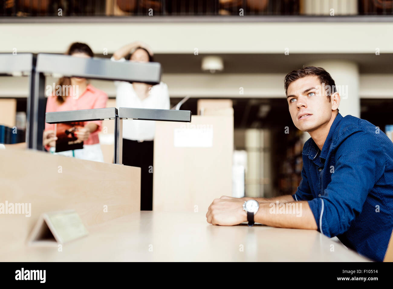 Gut aussehend Student am Schreibtisch sitzt und das Studium in einer Bibliothek Stockfoto