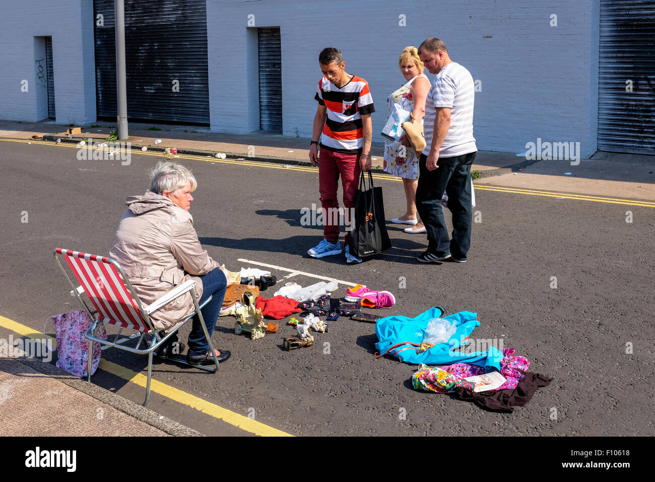 Frau verkaufen gebrauchte und alte Kleidung auf der Straße in der Nähe von The Barras, berühmten Straßenmarkt, Glasgow, Scotland, UK Stockfoto