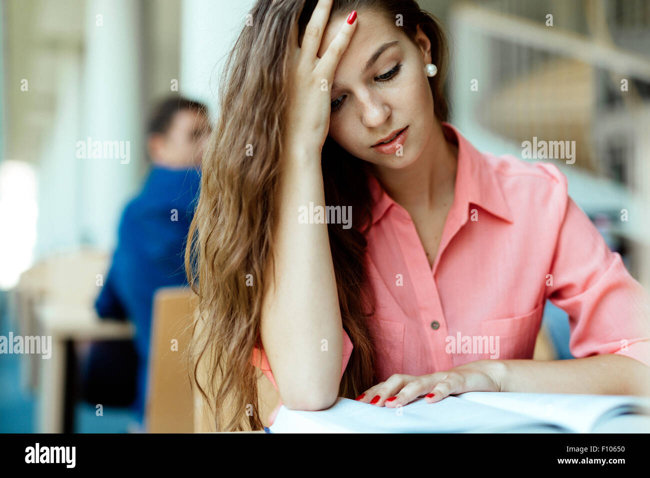 Weibliche Studenten studieren und lesen in einer Bibliothek aber ist eine harte Zeit Verständnis des Materials Stockfoto