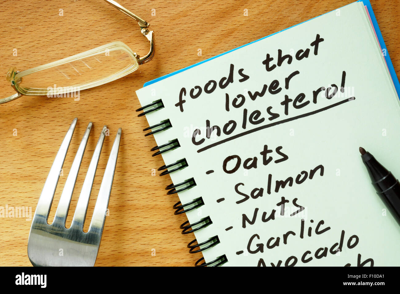Papier mit Lebensmitteln, die Cholesterin-Liste auf einem Holzbrett zu senken. Stockfoto