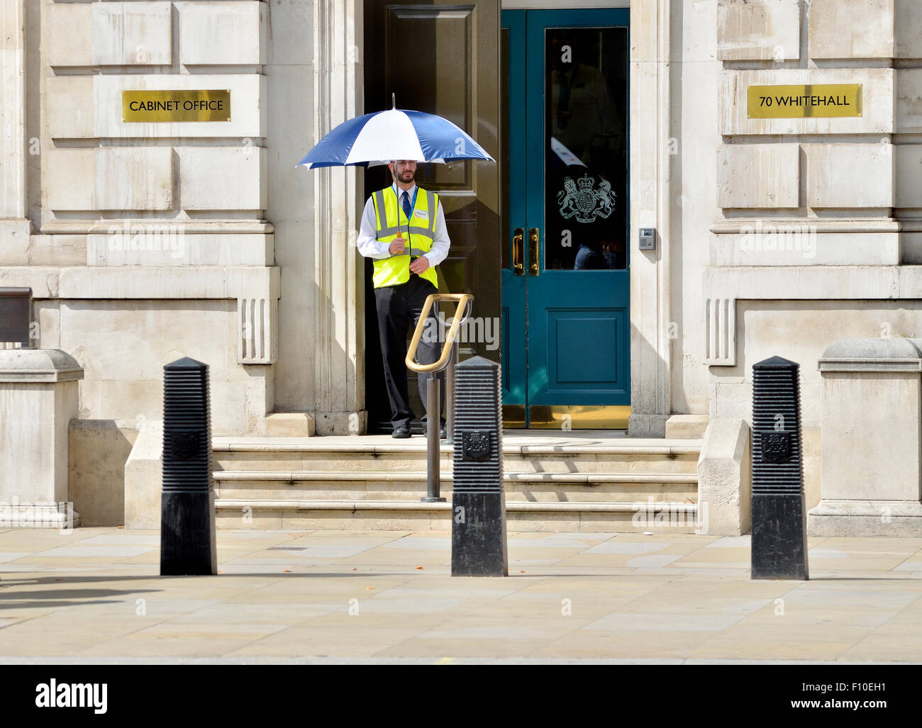 London, England, Vereinigtes Königreich. Wachmann außerhalb des Cabinet Office, 70 Whitehall, hält einen Regenschirm an einem sonnigen Tag im August Stockfoto