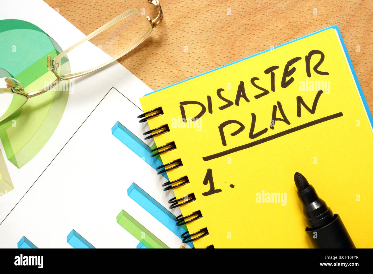 Notizblock mit Katastrophenplan auf einem Holztisch. Stockfoto